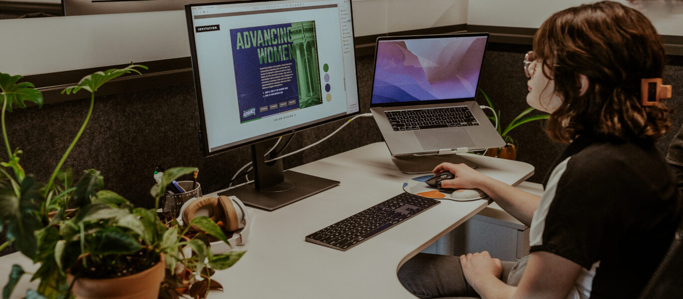 Woman sitting at a desk with two computers