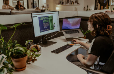 Woman sitting at a desk with two computers