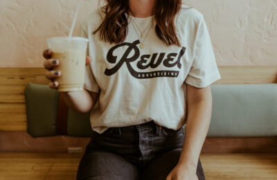 Woman wearing a Revel Advertising t-shirt holding a cup of coffee